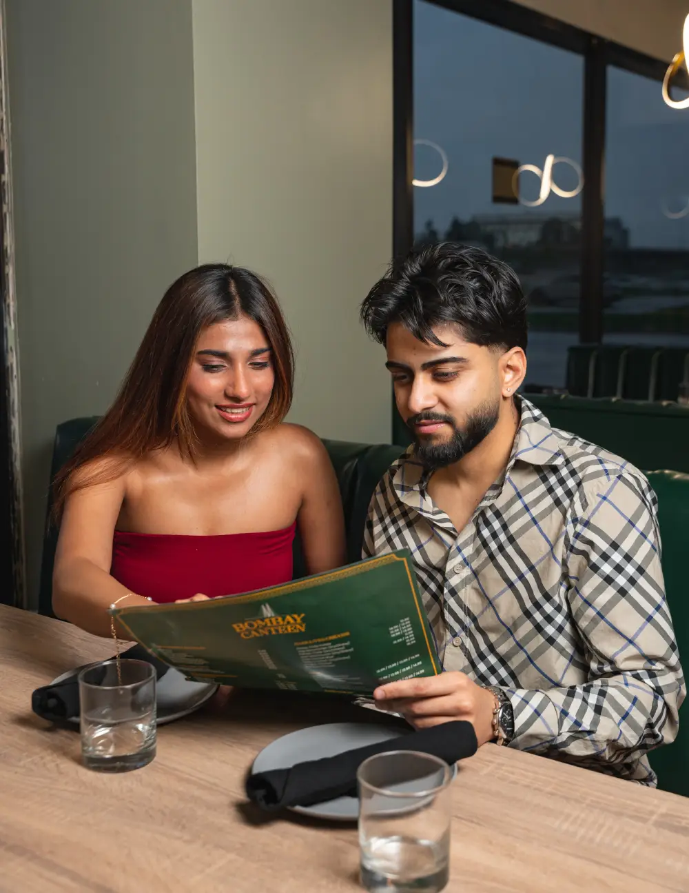 Couple sitting in a booth reading the Bombay Canteen menu